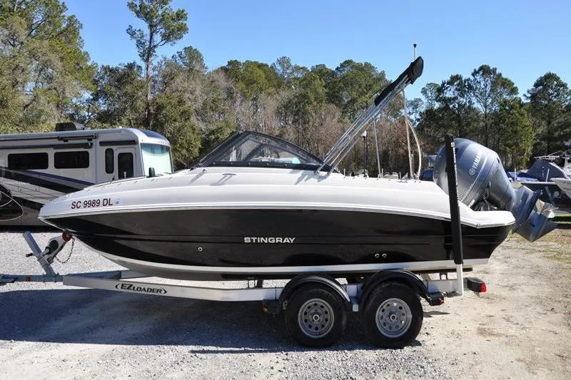 Slide: The Image of 2021 Stingray 201 DS boat on trailer, parked outdoors with trees in background. - 5