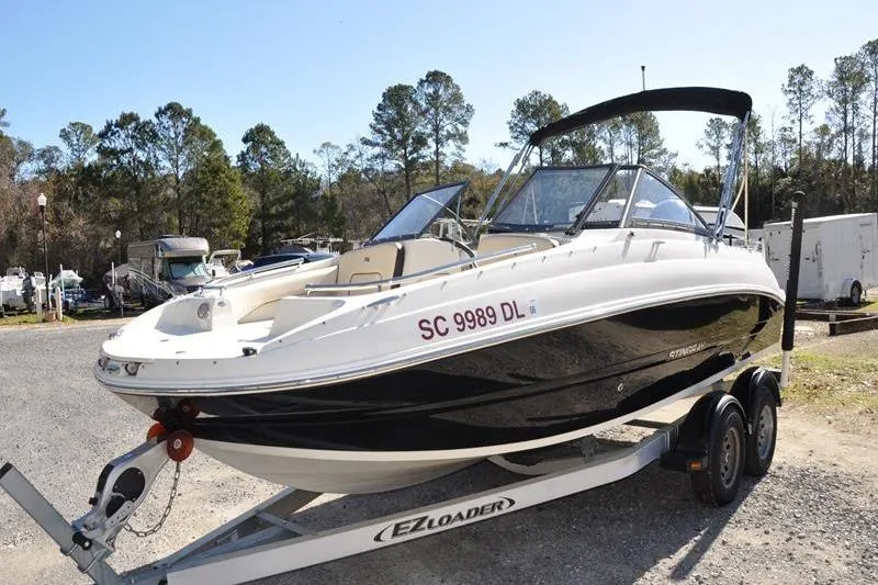 Slide: The Image of 2021 Stingray 201 DS boat on trailer, parked outdoors with trees in background. - 7