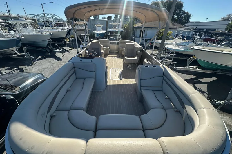 Slide: The Image of 2018 Bennington 24 SSRX pontoon boat with spacious seating and canopy, docked among other boats. - 6