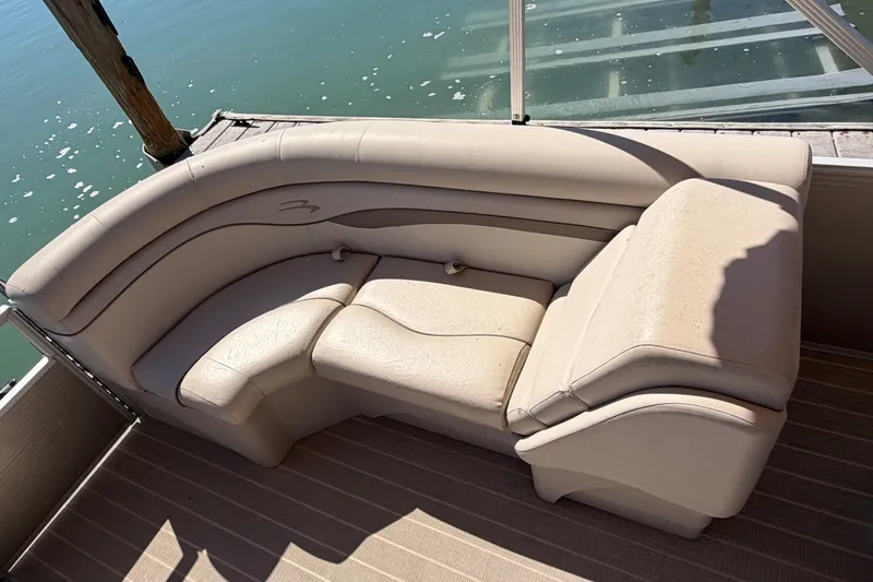 Slide: The Image of 2018 Bennington 24 SSRX boat with beige seating on a sunny day by the water. - 7