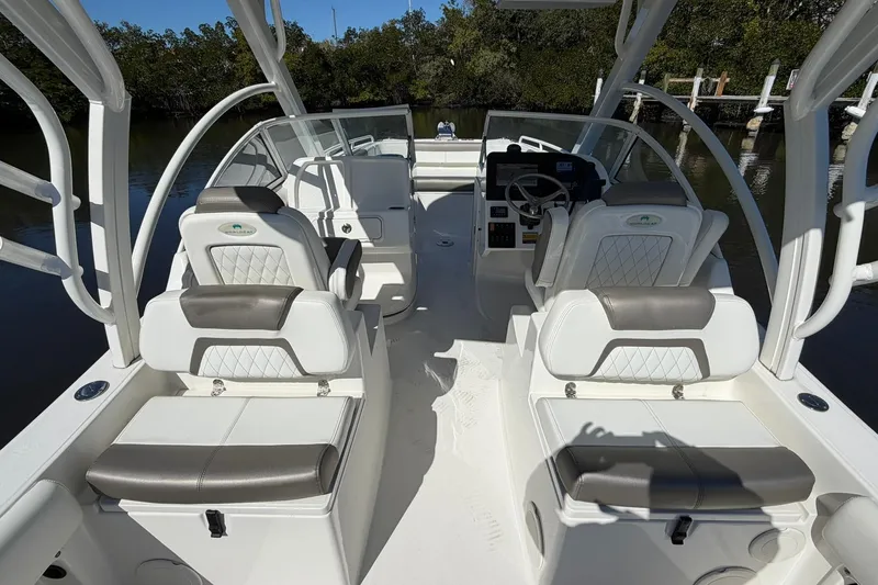 Slide: The Image of 2023 World Cat 255 DC boat interior with seating and steering wheel, docked near trees. - 24