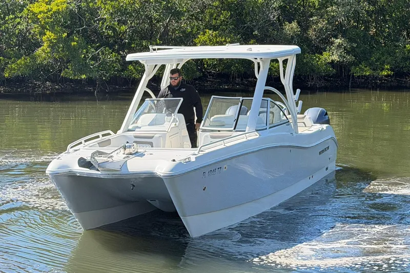 Slide: The Image of 2023 World Cat 255 DC boat navigating calm waters with lush greenery background. - 4