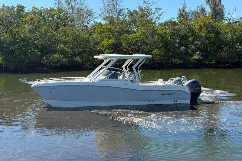 Slide: The Image of 2023 World Cat 255 DC boat cruising on a calm river with lush greenery. - 6