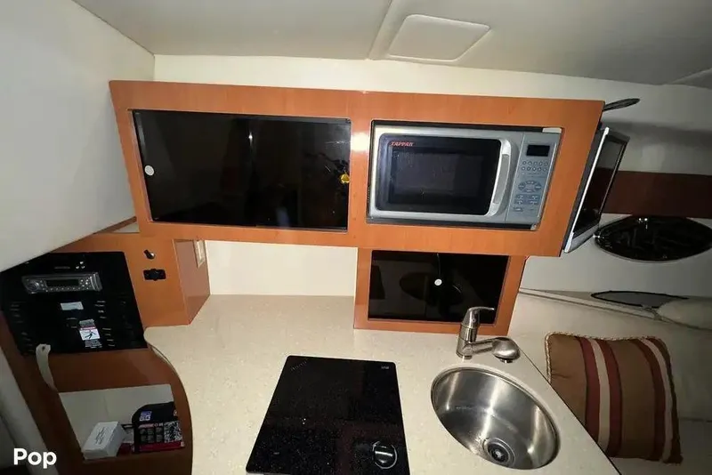 Slide: The Image of 2007 Maxum 2600 SE boat interior kitchen with microwave, sink, and storage cabinets. - 4
