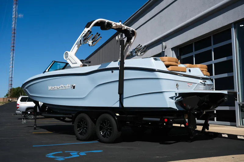 Slide: The Image of 2026 MasterCraft XT24 boat on trailer, parked outside a modern building. - 4