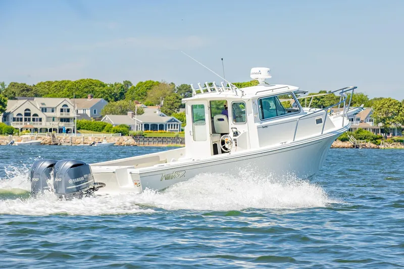 Slide: The Image of Manufacturer Provided Image: 2026 Parker 287 Explorer boat cruising on water near coastal homes. - 2