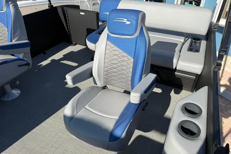 Slide: The Image of 2024 Bennington SSB-SPS boat interior with blue and gray seating, cup holders, and modern design. - 12