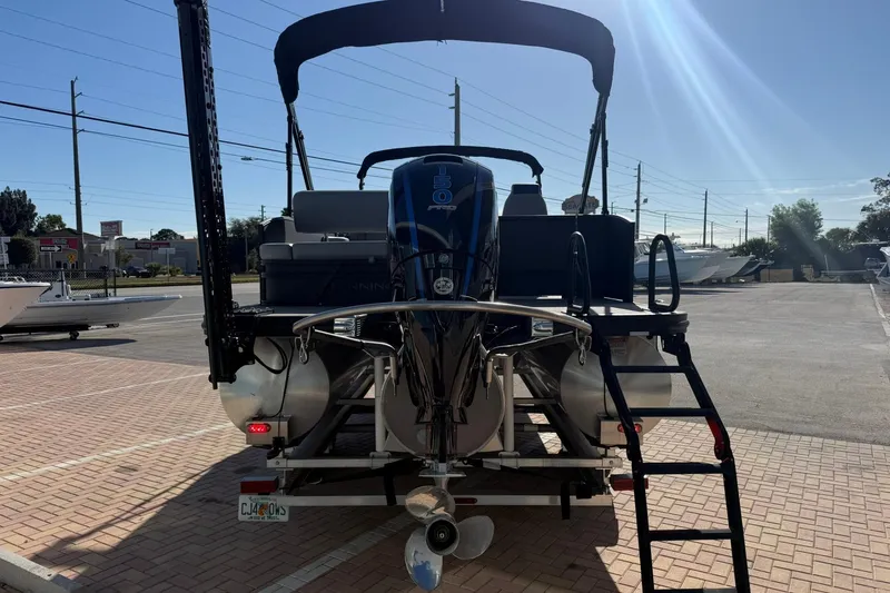 Slide: The Image of 2024 Bennington SSB-SPS pontoon boat with outboard motor, parked on brick pavement. - 2