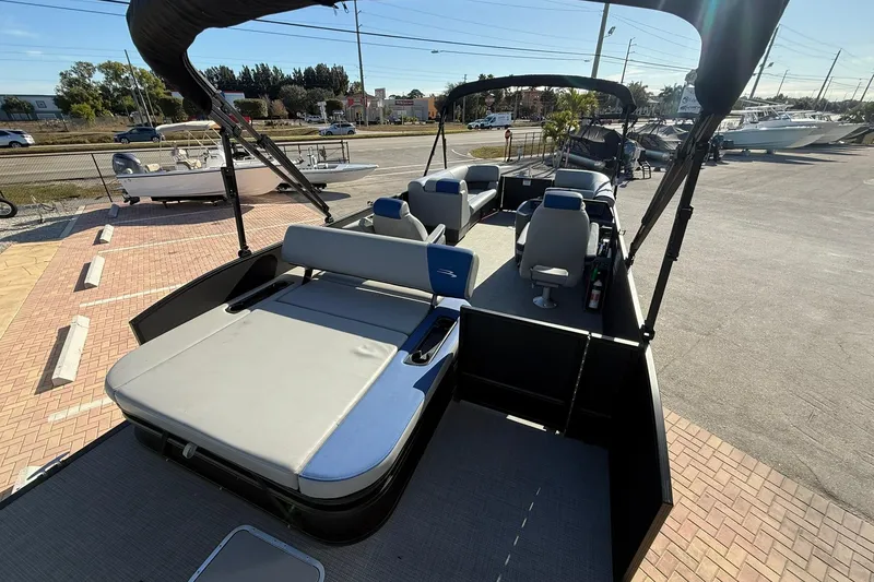 Slide: The Image of 2024 Bennington SSB-SPS pontoon boat with spacious seating and sunshade, parked on a paved lot. - 6