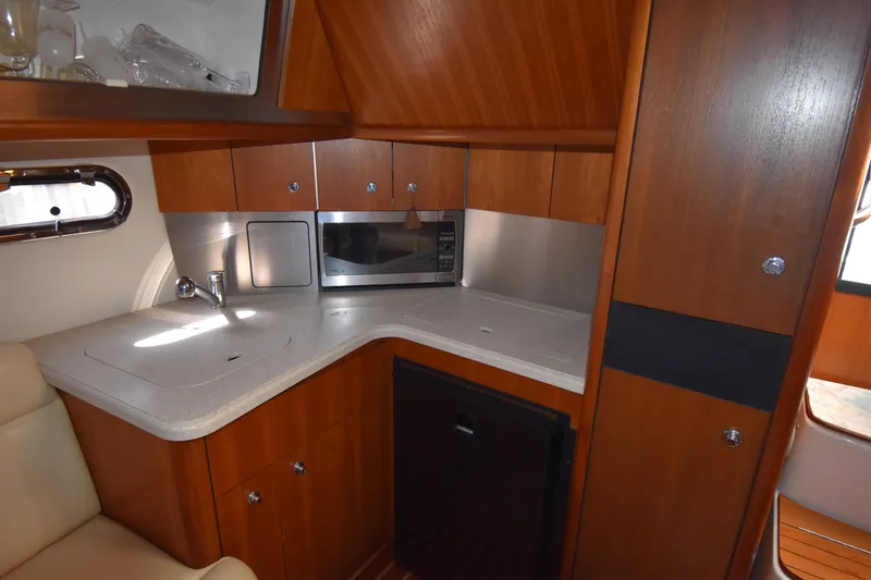 Slide: The Image of 2006 Tiara Yachts 3600 Open galley with wood cabinetry, sink, microwave, and compact fridge. - 25