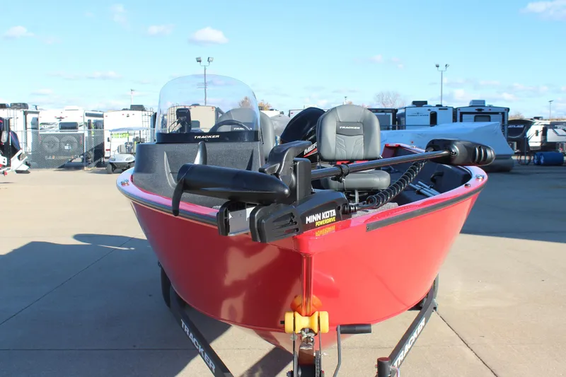 Slide: The Image of 2026 Tracker Pro Guide V-16 SC boat, red exterior, parked outdoors with Minn Kota motor. - 2