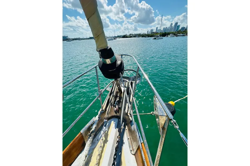 Slide: The Image of Bow of 1971 Alden Boothbay Explorer sailboat on calm water with city skyline. - 12