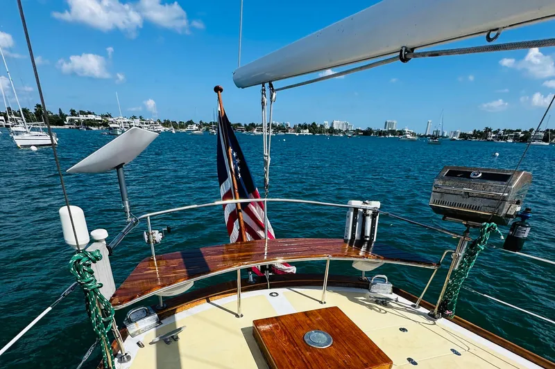Slide: The Image of Alden Boothbay Explorer 1971 sailboat on serene blue waters, featuring a wooden deck and American flag. - 67