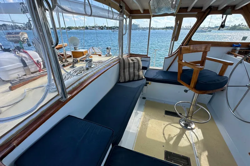 Slide: The Image of 1971 Alden Boothbay Explorer yacht interior with blue seating and wooden helm, overlooking serene waters. - 71