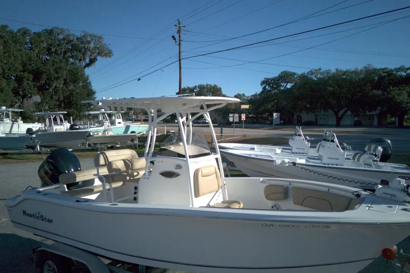Slide: The Image of 2019 NauticStar 2200XS Offshore boat displayed outdoors on a sunny day. - 12