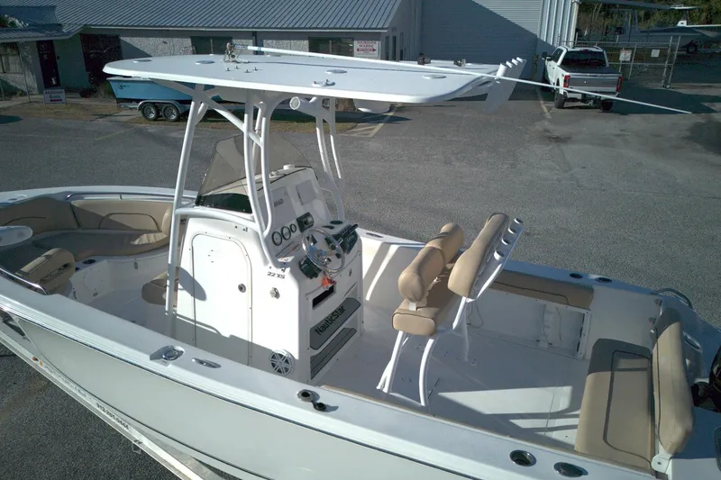 Slide: The Image of 2019 NauticStar 2200XS Offshore boat with T-top and seating, parked outdoors. - 7