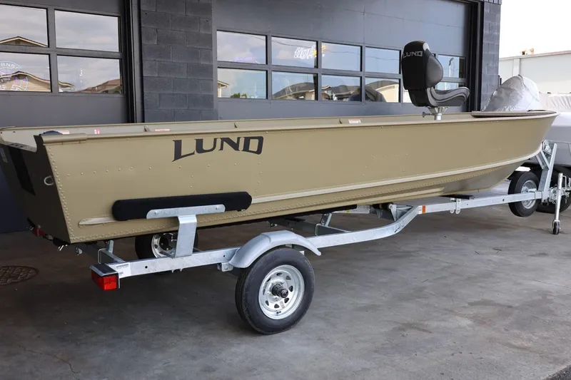 Slide: The Image of 2025 Lund SSV-18 Tiller boat on trailer, parked outside a garage. - 5