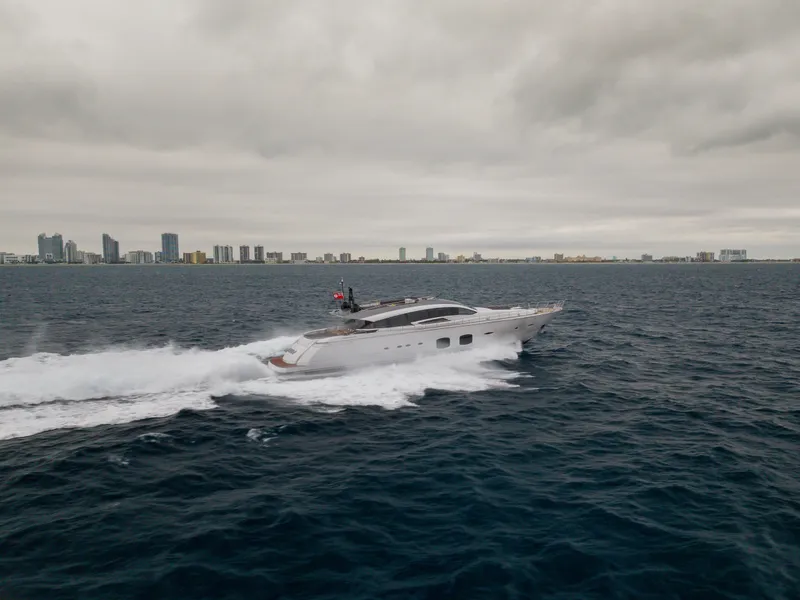 Slide: The Image of 2018 Pershing 108 yacht cruising on open water with city skyline in background. - 20