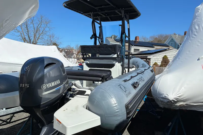 Slide: The Image of 2024 Zodiac Pro 5.5 inflatable boat with steering console and seating, docked outdoors. - 2