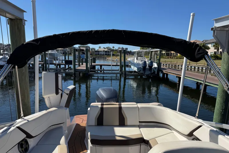Slide: The Image of 2016 Regal 23 OBX boat interior with seating and steering wheel at a marina. - 13