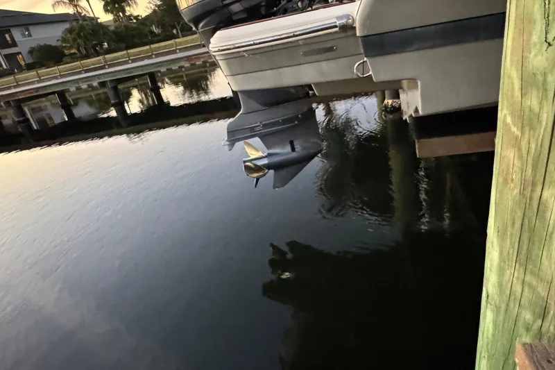 Slide: The Image of 2016 Regal 23 OBX boat docked, showing outboard motor and calm water reflection. - 33