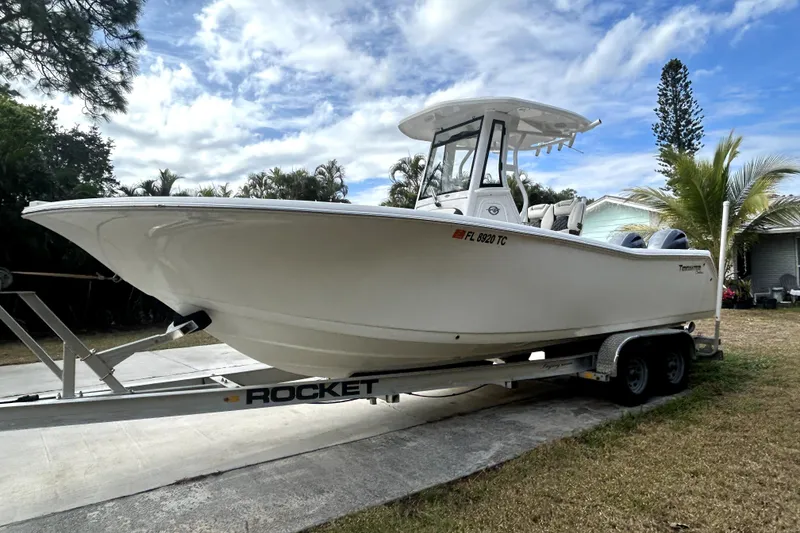 The Image of 2022 Tidewater 256 CC Adventure boat on trailer, parked outdoors under a cloudy sky. - 0