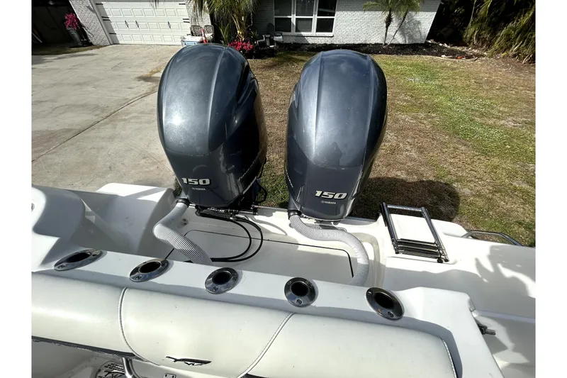 Slide: The Image of 2022 Tidewater 256 CC Adventure with dual Yamaha 150 outboard engines, parked in driveway. - 1