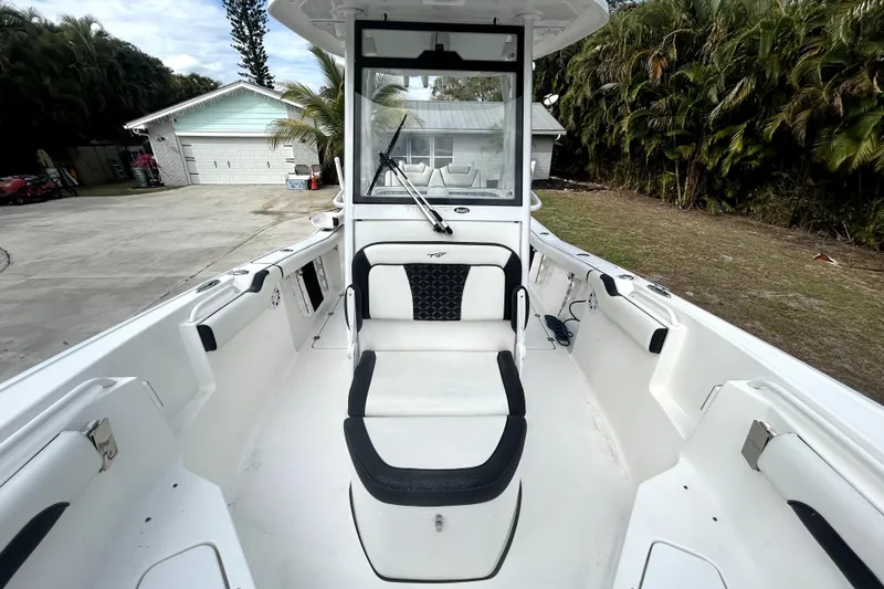 Slide: The Image of 2022 Tidewater 256 CC Adventure boat interior with seating and console, parked outdoors. - 13
