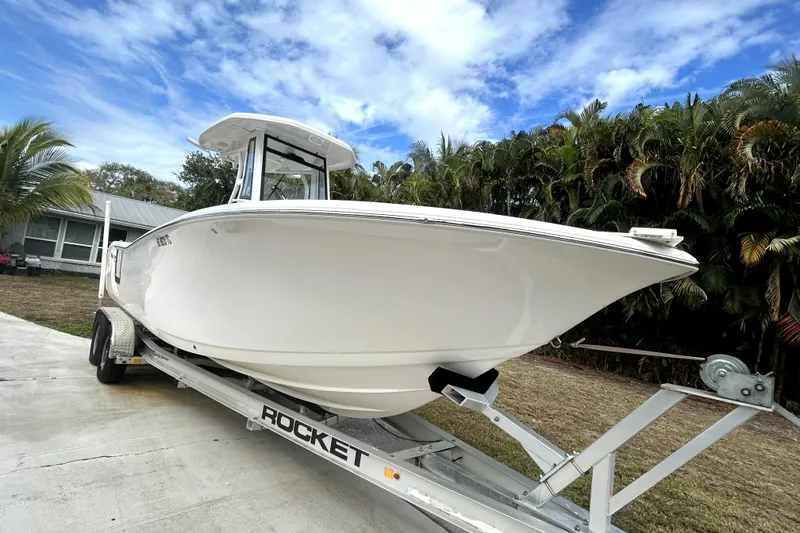 Slide: The Image of 2022 Tidewater 256 CC Adventure boat on trailer, surrounded by palm trees and blue sky. - 19