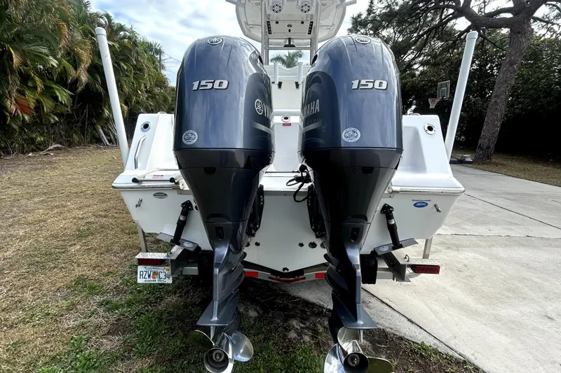 Slide: The Image of 2022 Tidewater 256 CC Adventure boat with dual Yamaha 150 engines, parked outdoors. - 2