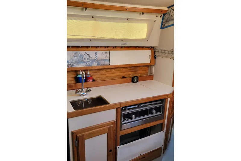 Slide: The Image of 1993 Catalina 28 yacht kitchen with sink, stove, and wooden cabinetry. - 16
