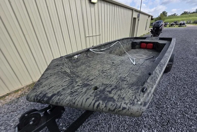 Slide: The Image of 2026 Tracker Grizzly 1650 T Prairie Wings Edition boat on gravel near a building. - 4