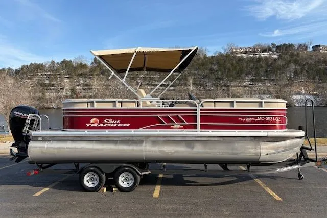 Slide: The Image of 2023 Sun Tracker Party Barge 22 DLX pontoon boat on trailer, parked by a scenic lake. - 44