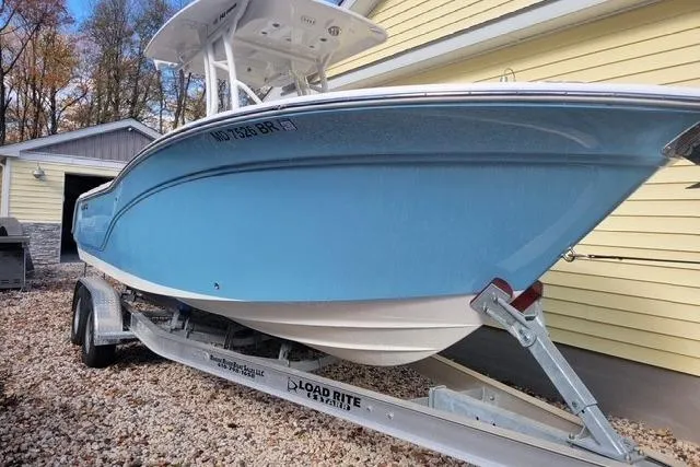 Slide: The Image of 2022 Sea Fox 248 Commander boat on trailer, parked beside a yellow building. - 2