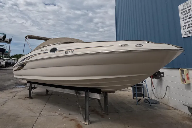 Slide: The Image of 2001 Sea Ray 240 Sundeck boat on dry dock, blue building background. - 13