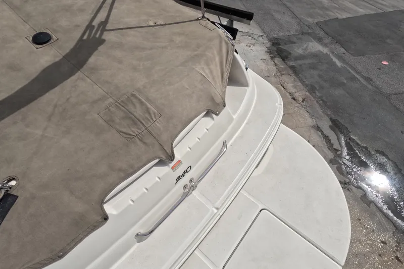 Slide: The Image of 2001 Sea Ray 240 Sundeck boat with cover, docked on a concrete surface. - 26