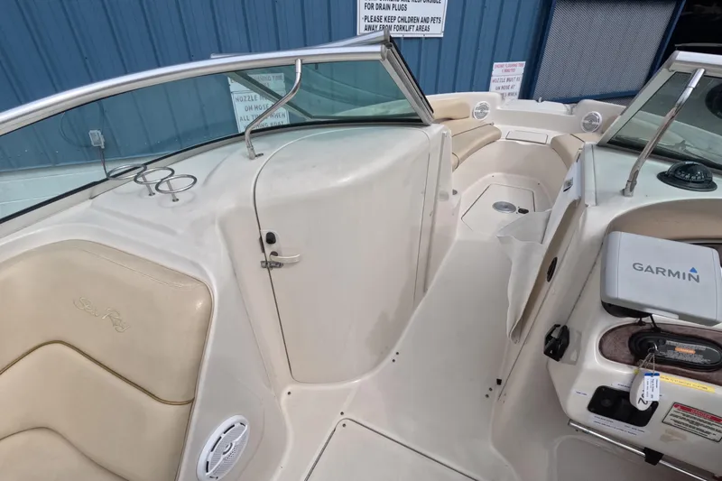 Slide: The Image of 2001 Sea Ray 240 Sundeck interior with Garmin navigation, beige seating, and cup holders. - 32