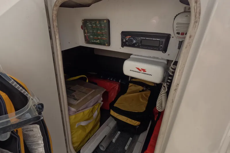 Slide: The Image of Storage compartment of a 2001 Sea Ray 240 Sundeck with safety equipment and radio. - 49