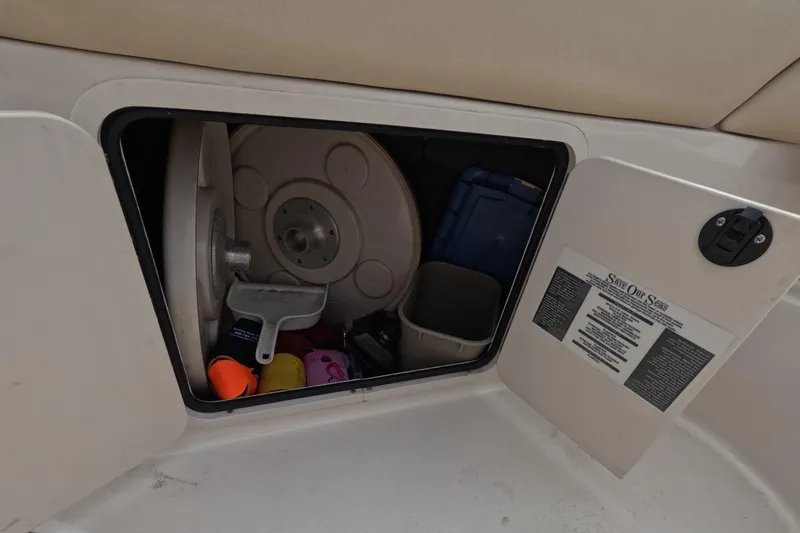 Slide: The Image of Storage compartment on a 2001 Sea Ray 240 Sundeck boat with various items inside. - 57