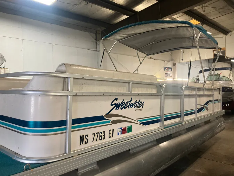 The Image of 2000 Godfrey Sweetwater 24ELITE pontoon boat under a shelter. - 0