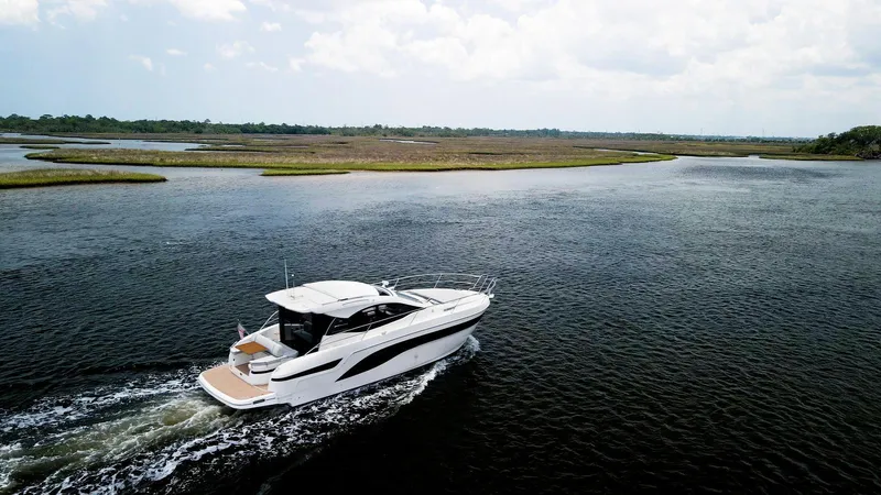 Slide: The Image of 2022 Bavaria SR41 yacht cruising on a serene lake under a cloudy sky. - 4