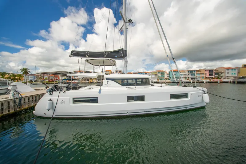Slide: The Image of 2023 Lagoon 46 catamaran docked in a marina with colorful buildings. - 11