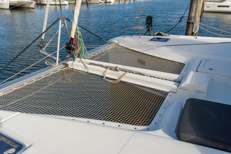 Slide: The Image of 2023 Lagoon 46 catamaran deck with netting, docked in a marina. - 111