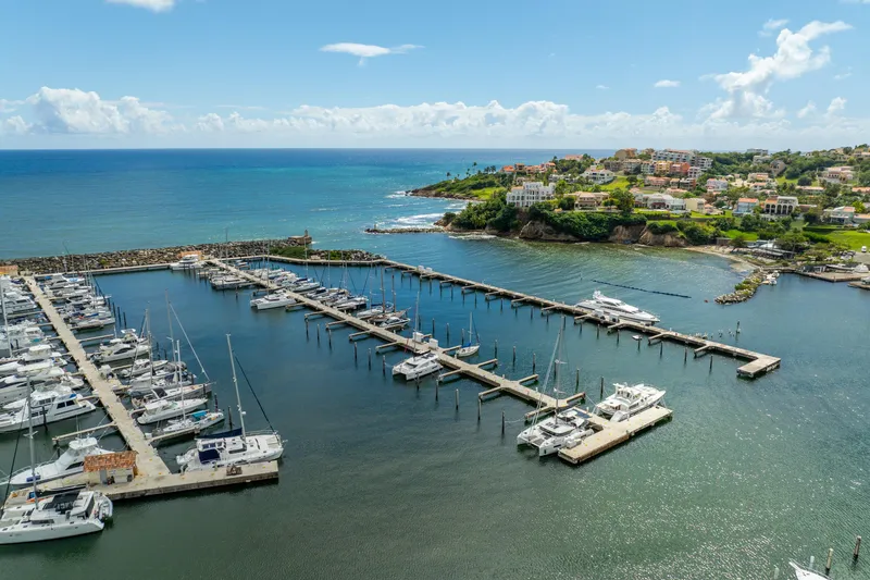 Slide: The Image of Aerial view of marina with Lagoon 46 catamarans, 2023 model, docked by the scenic coastline. - 116