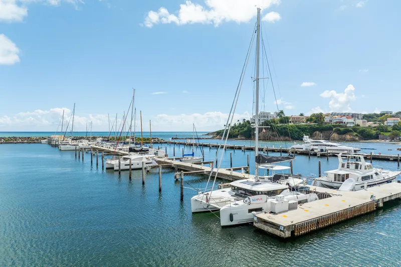 Slide: The Image of Marina with 2023 Lagoon 46 catamarans docked under a clear blue sky. - 117