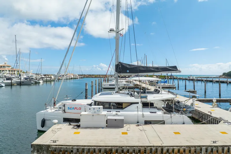 Slide: The Image of 2023 Lagoon 46 catamaran docked at a marina under a clear blue sky. - 120