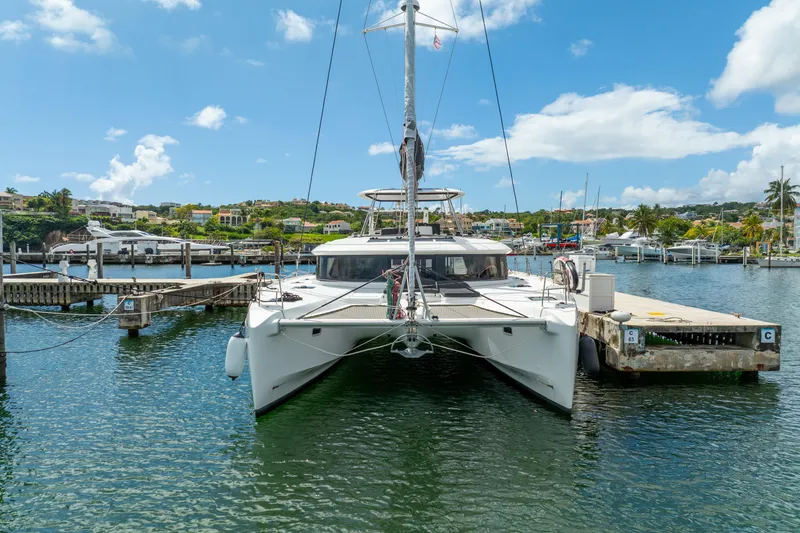 Slide: The Image of 2023 Lagoon 46 catamaran docked in a sunny marina, surrounded by scenic waterfront views. - 125