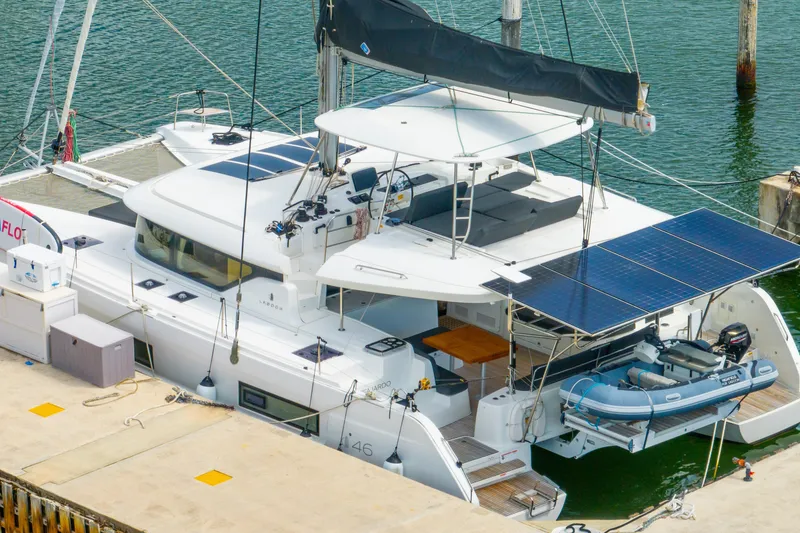 Slide: The Image of 2023 Lagoon 46 catamaran docked, featuring solar panels and an inflatable boat. - 126