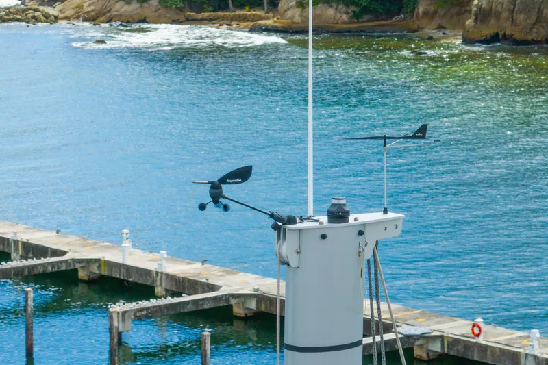 Slide: The Image of Mast of 2023 Lagoon 46 catamaran with wind instruments, dock, and scenic coastal background. - 129