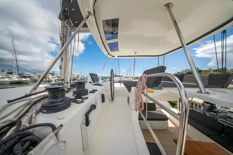 Slide: The Image of 2023 Lagoon 46 yacht cockpit with steering wheel, winches, and seating in marina. - 13